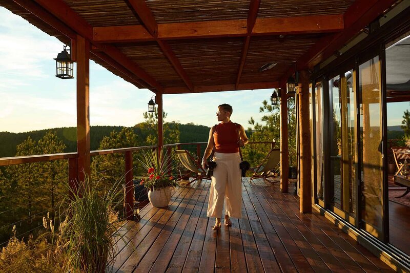 Kate Okenatez-Mahoney, a luxury destination elopement wedding photographer walks down a sunset warmed patio surrounding a luxury safari tent.  