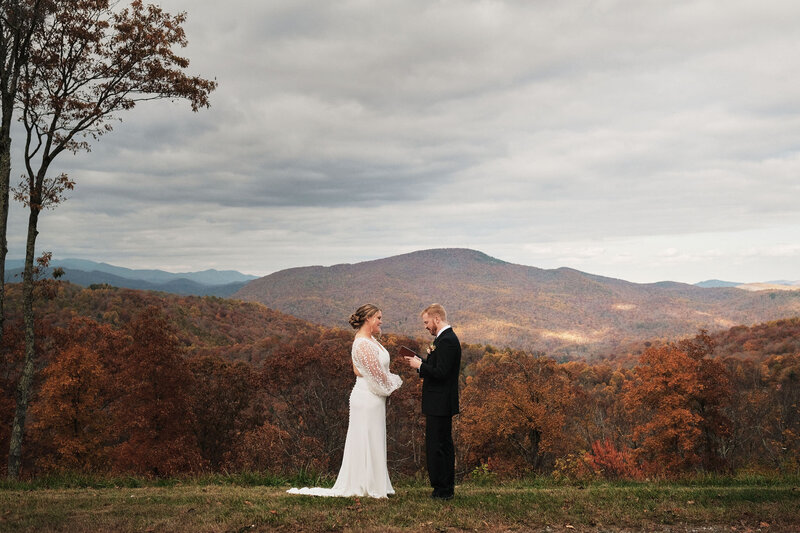 Couple saying their vows with fall foliage behind them