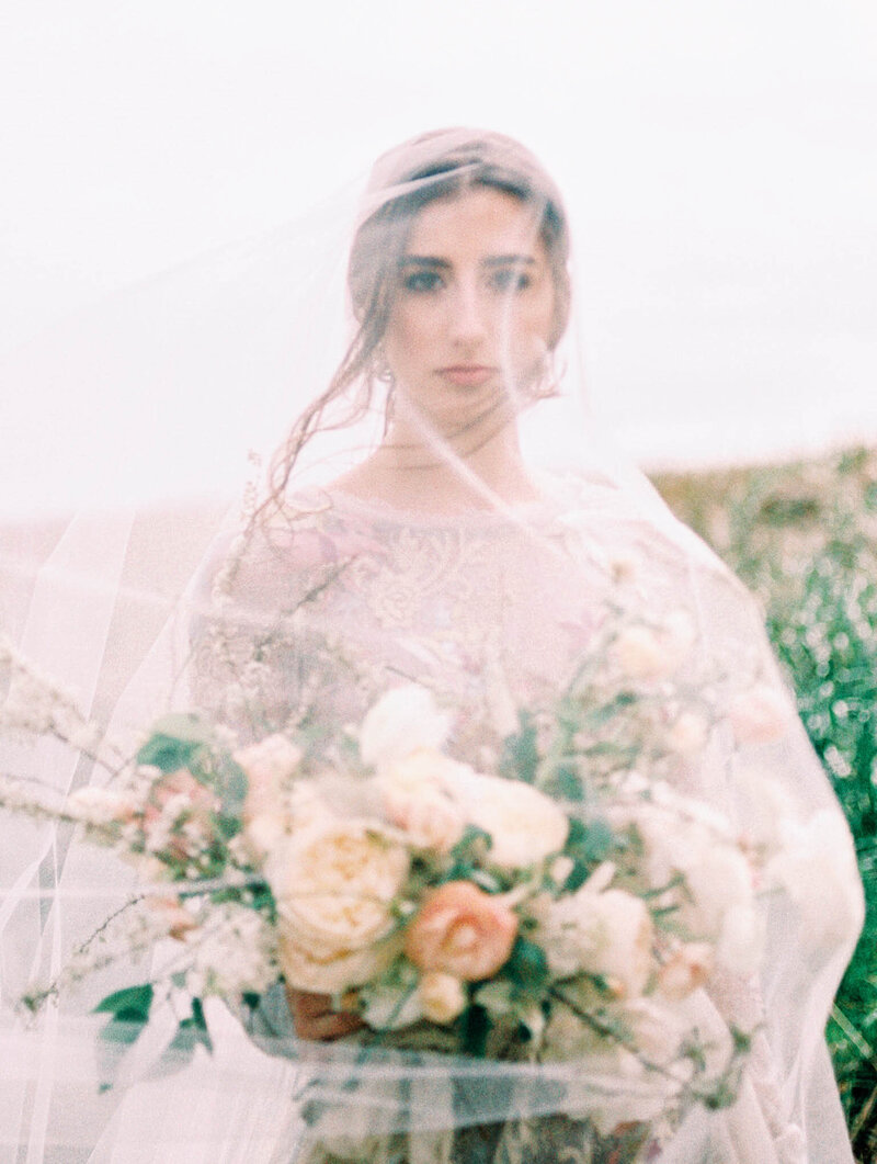 Beautiful portrait of bride in veil  holding stunning flowers