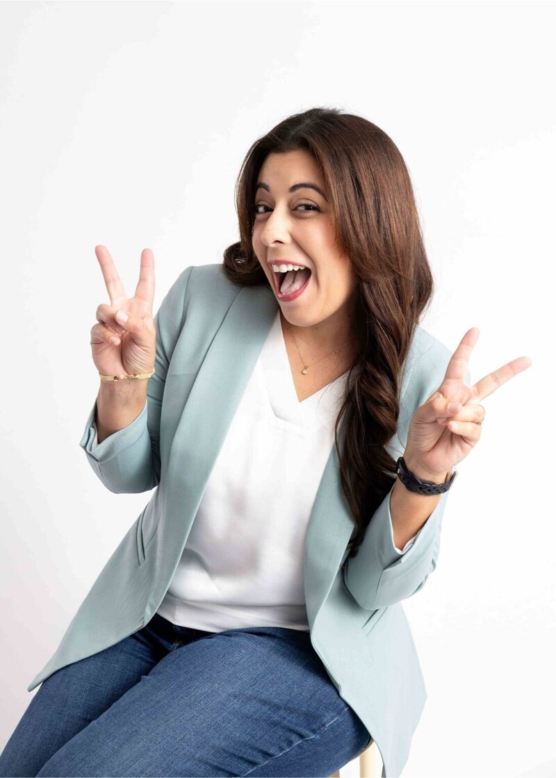 Jennis from She Blooms Studio, Showit web designer for mom entrepreneurs, smiling and holding up peace signs.