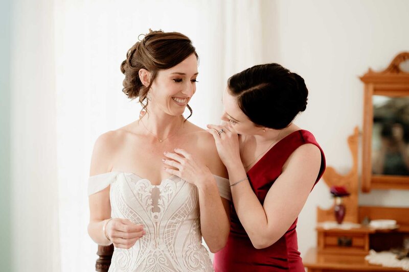 Maid of honor assisting the bride in wearing her necklace