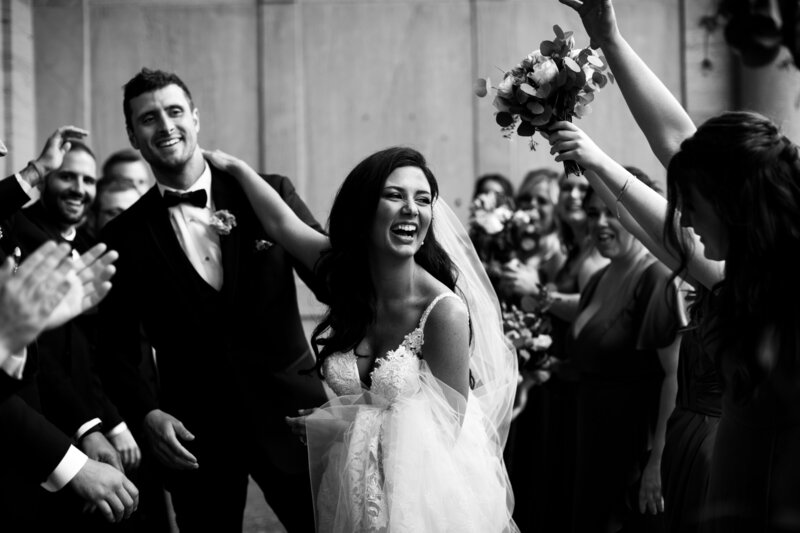Couple with their wedding party laughing on their wedding day