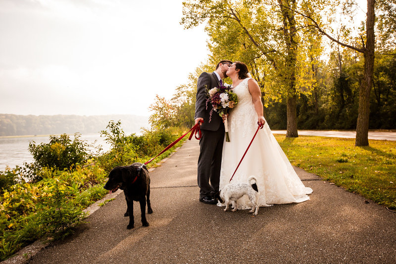 Bride and groom walk their dogs on a path at Presque Isle State Park