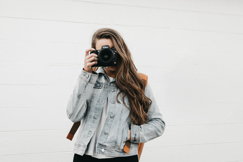 photographer with camera sitting in front of white wall