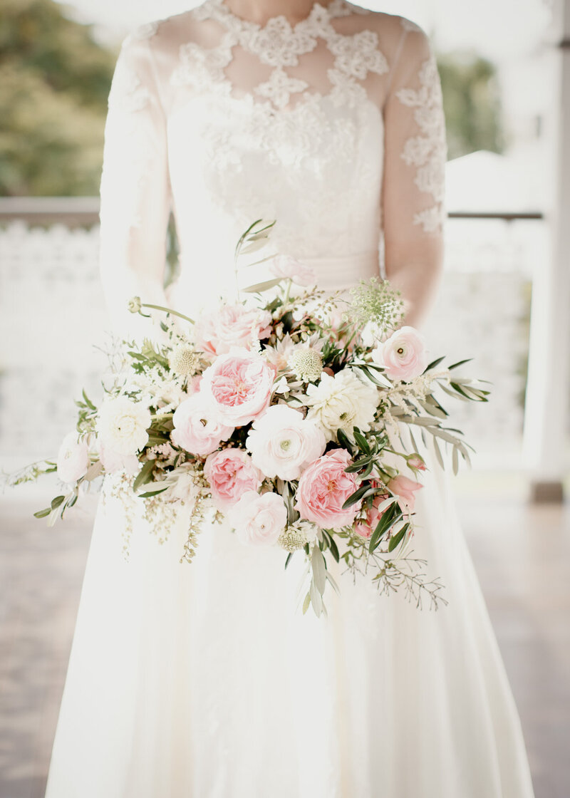 Bride wearing her white laced wedding dress and a soft pink and white bouquet