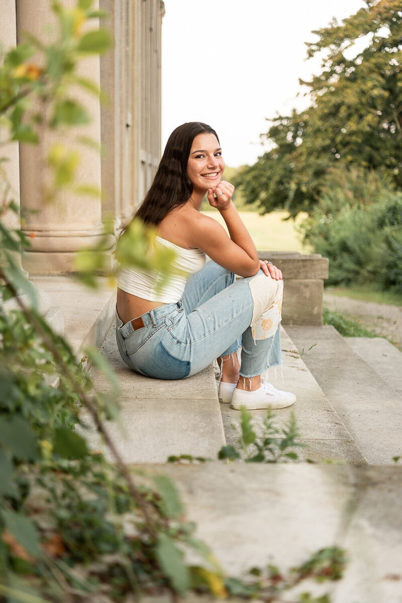 Senior girl sitting on steps with white shirt and jeans