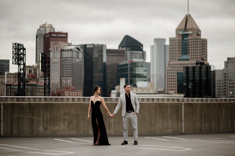 couple holding hands standing on top of a roof