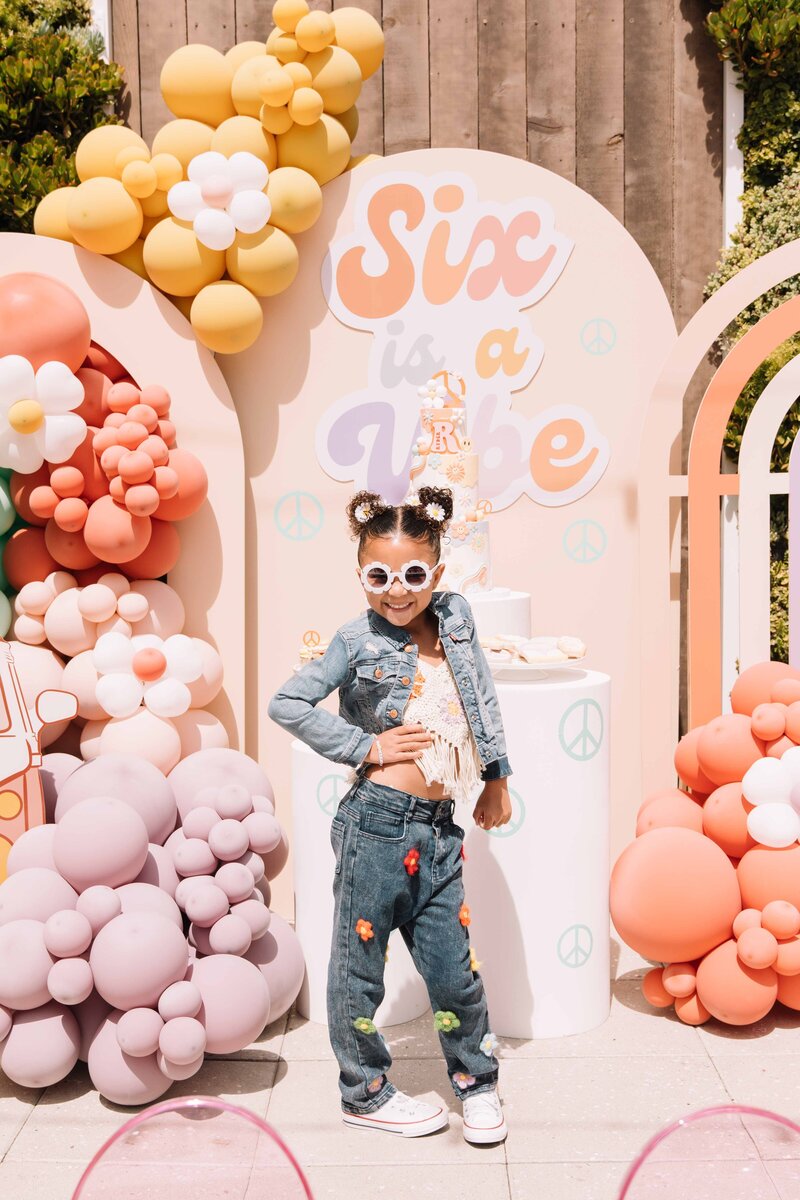 A young girl strikes a pose in front  on a  custom made set piece at Hart and  Main