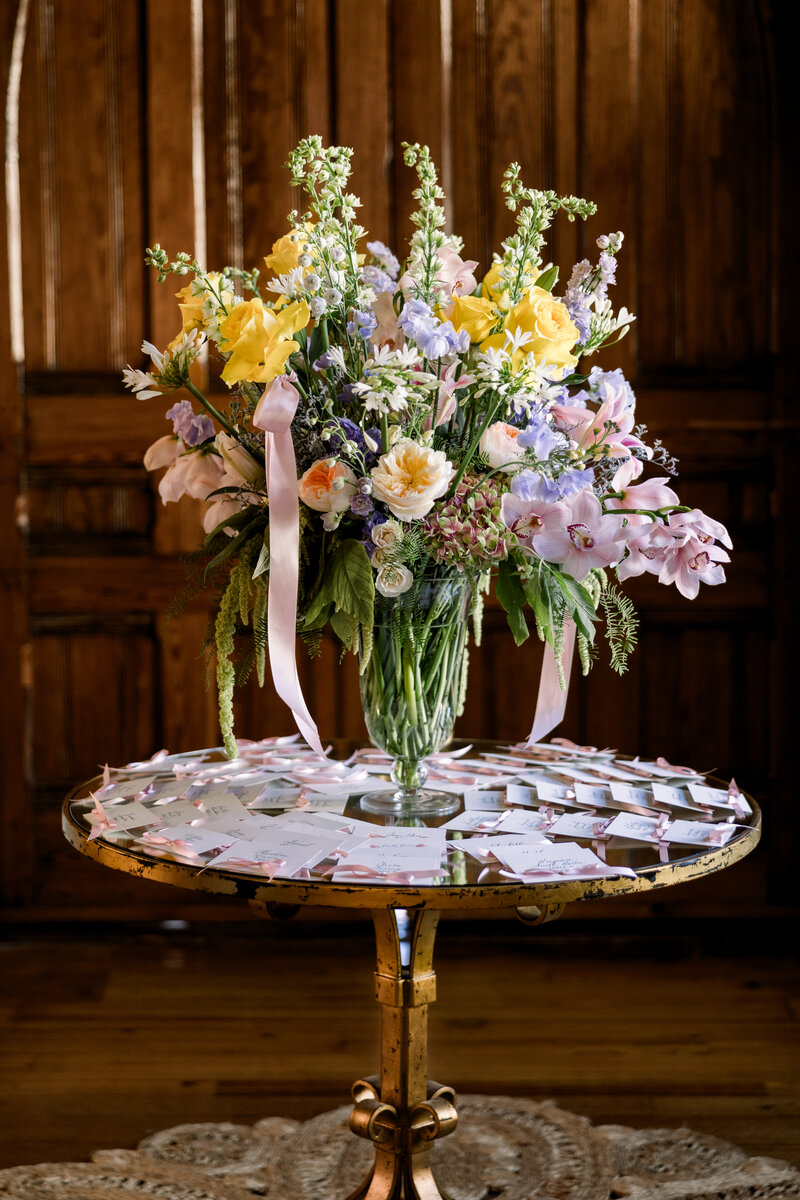 Beautiful floral arrangement with place cards surrounding it on a table