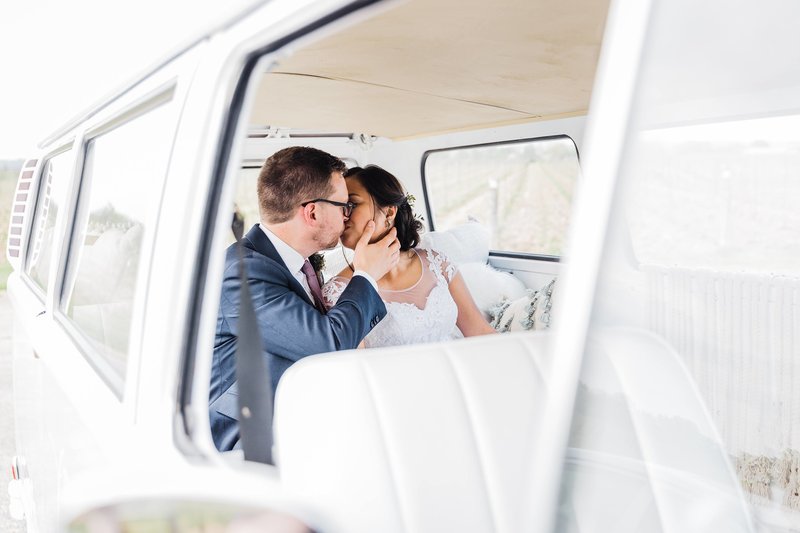 Bride and groom share a kiss in the back of their Kombi van wedding car from Long Weekend Bus