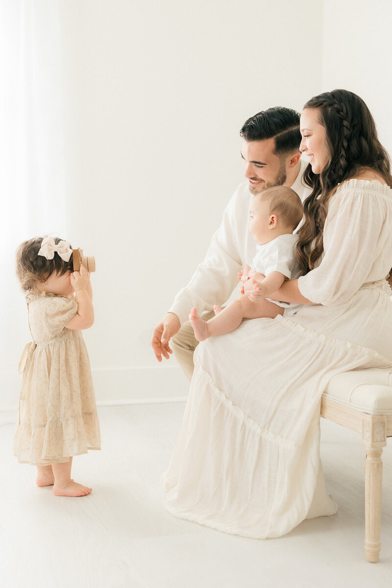 Family of 4 playing together while being photographed in an all white studio by NJ newborn photographer