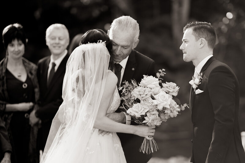 Father kisses the bride before giving her hand to the groom