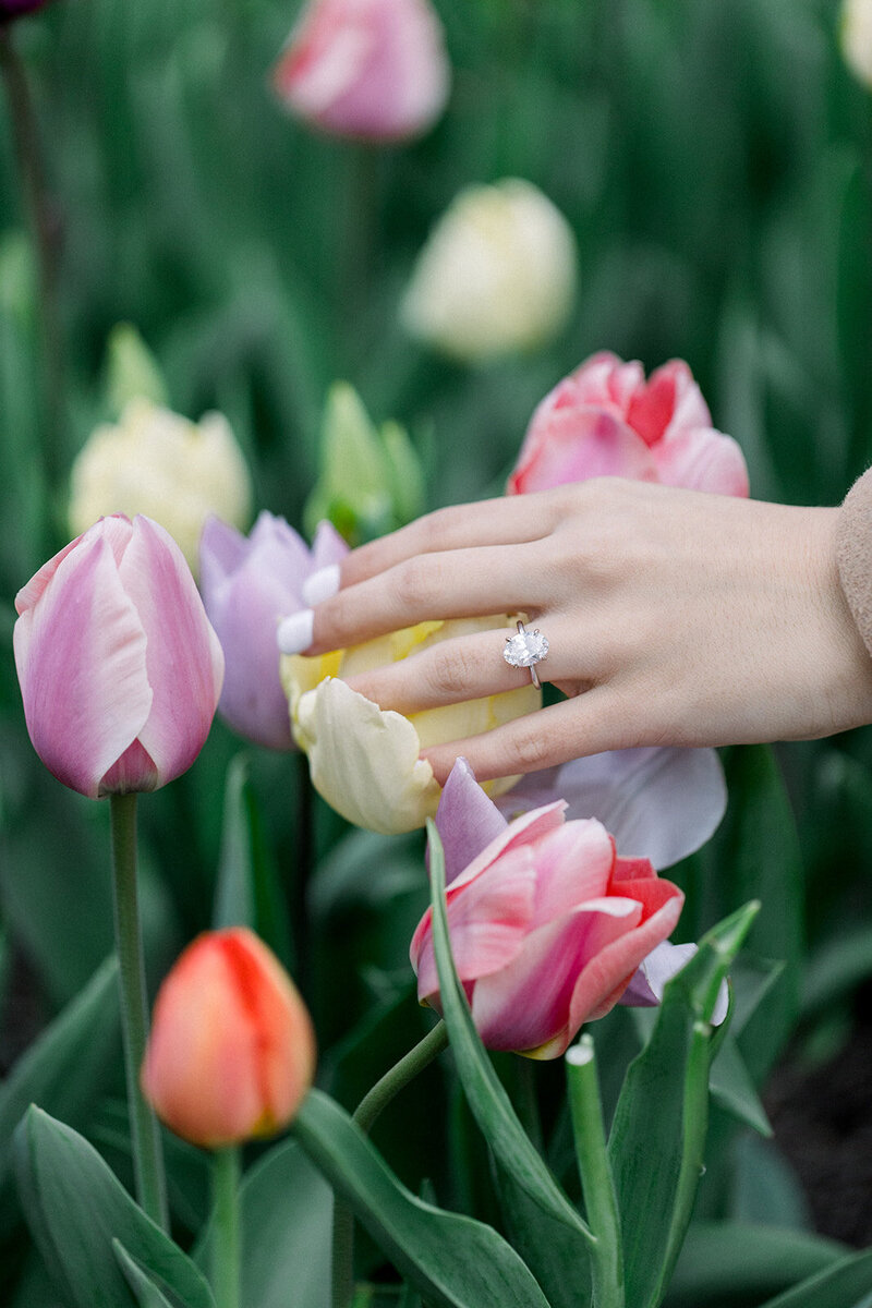 engaged bride touching flowers with an oval shaped ring on