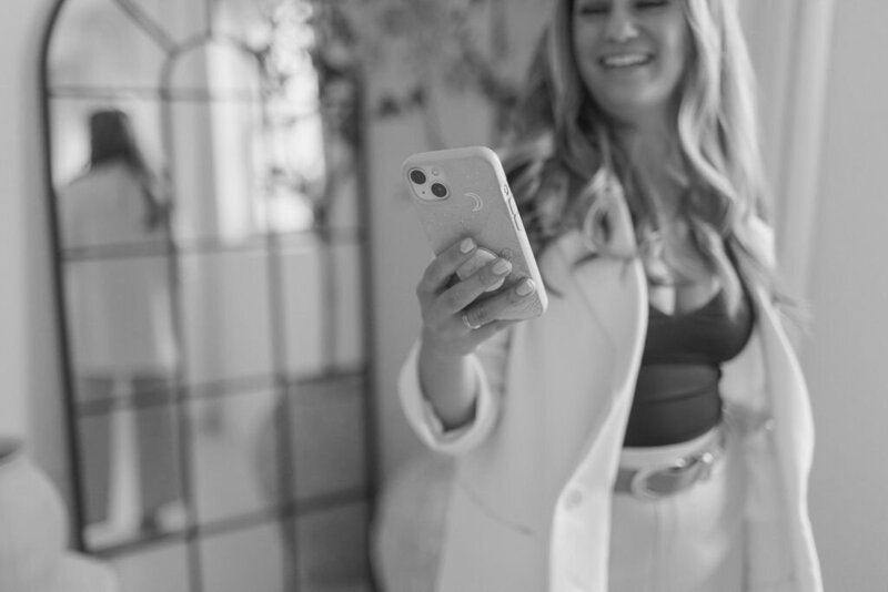 Martina Biljan, copywriter and creative brand strategist  smiling looking at iphone