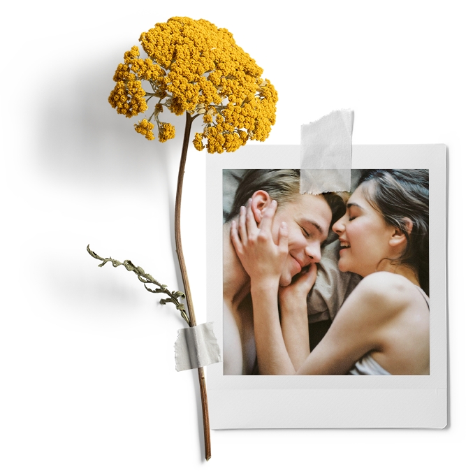 yellow flower taped onto polaroid of couple laying in bed and smiling