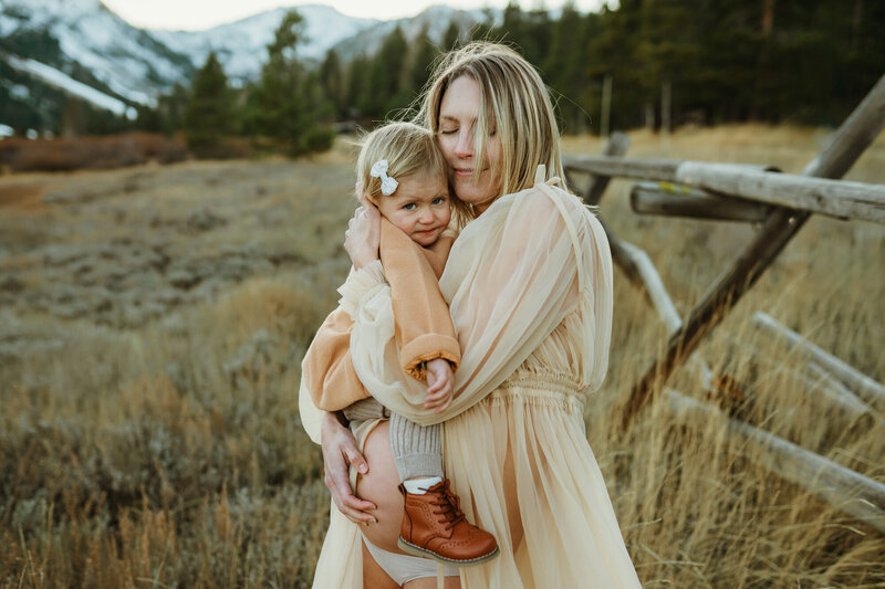 Pregnant mom holding toddler daughter at palisades Tahoe City