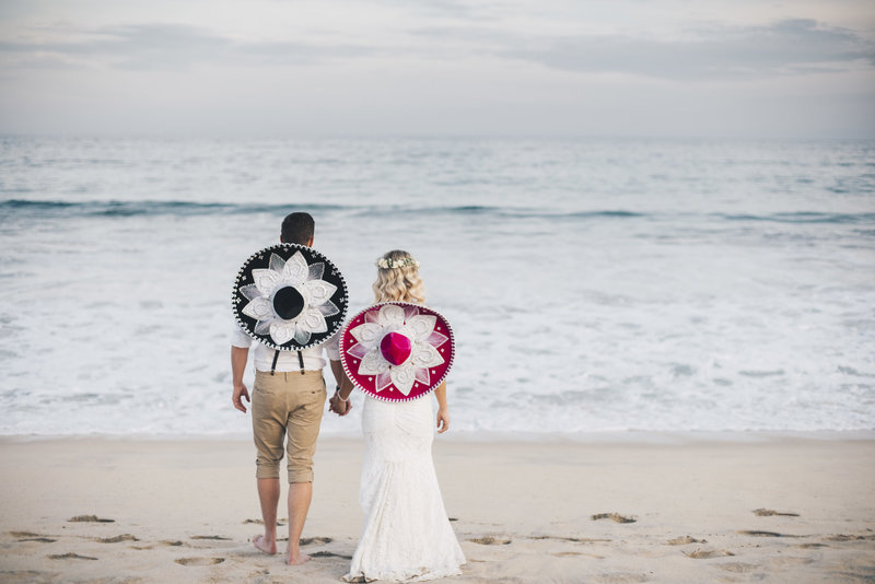 Bride and Groom standing on the beach wearing sombreros
