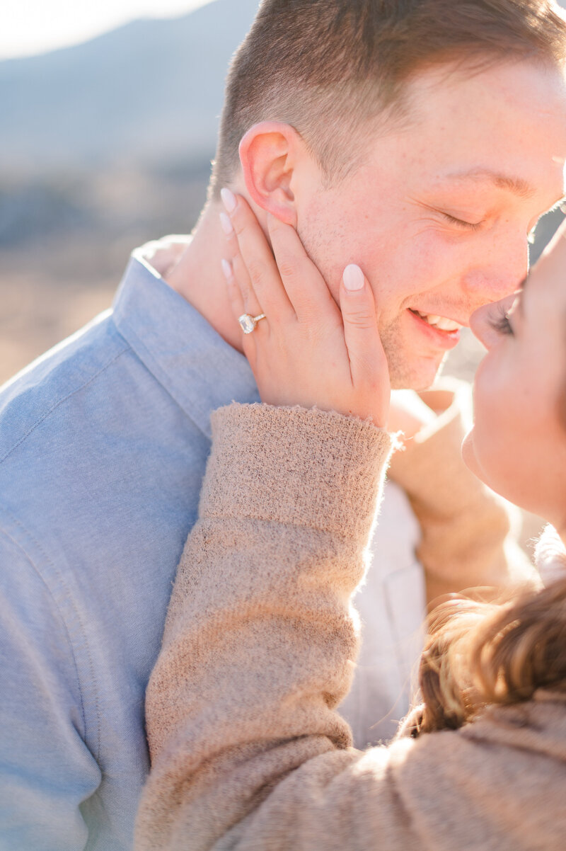 Woman holding a man's face close for a kiss during their engagement session.
