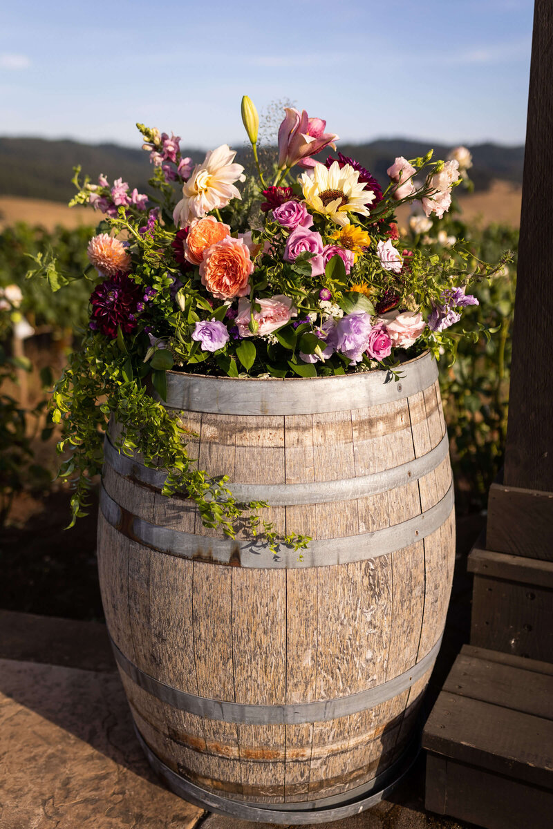 Floral centerpiece sits on top of a wine barrel.