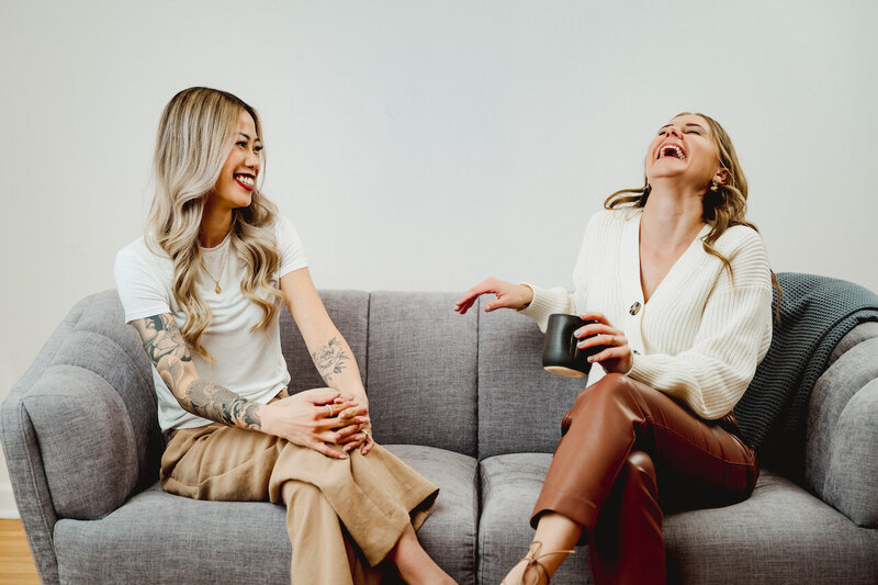 Two ladies on a couch laughing
