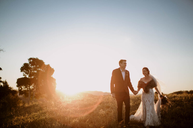 Wedding couple holding hands while walking during sunset at mountain top