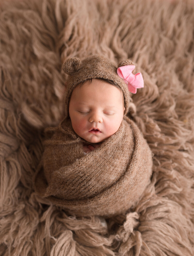 Newborn wrapped in brown knit swaddle with bear bonnet