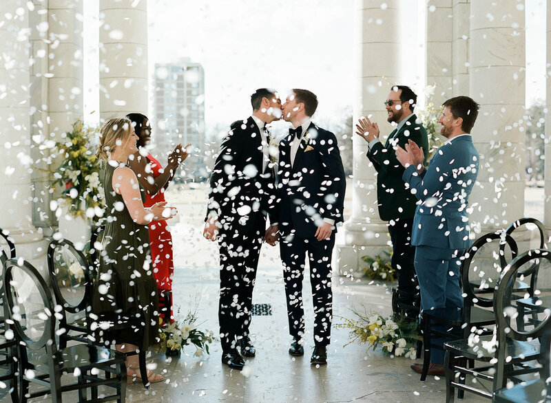 Grooms kiss among confetti at Cheesman Park Pavilion wedding