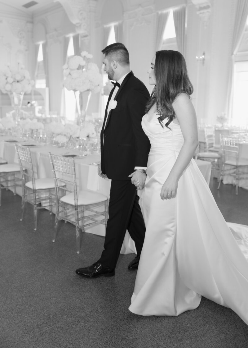 Bride and groom walk around their reception space before the guests site down.