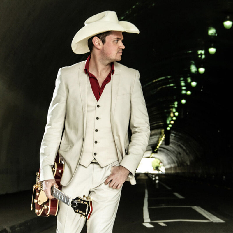Country Music Portrait Los Angeles Ben Klick standing in tunnel wearing white suit red shirt white cowboy hat green lights on roof of tunnel beside him