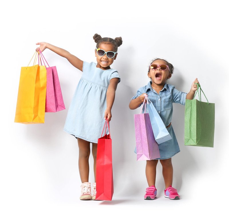 Excited children with shopping bags selecting products for 'What We're Loving' in Successful Black Parenting Magazine. Showcasing items from Black-owned businesses, this image captures the joy of discovering new family essentials.