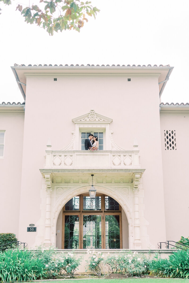 8-alisonbrynn-Radiant-LoveEvents-Maxwell-1-House-2-story-building-bride-groom--kissing-2nd-story-balcony-outdoors-romantic-elegant-timeless