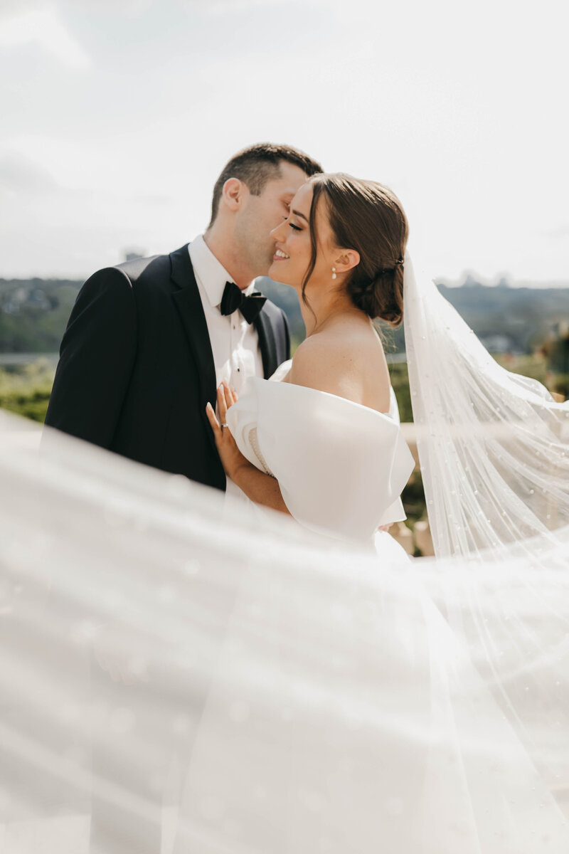 Groom kissing bride on cheek