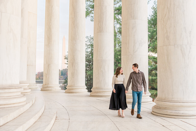 A man and woman hold hands as the walk inside of the Jefferson Memorial