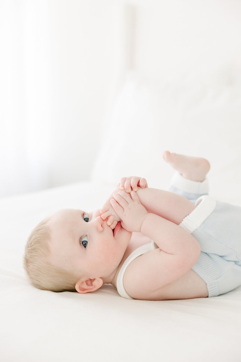 6 month old baby sticks his toes in his mouth during baby portrait session