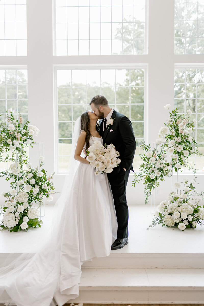 bride and groom kissing in front of giant windows