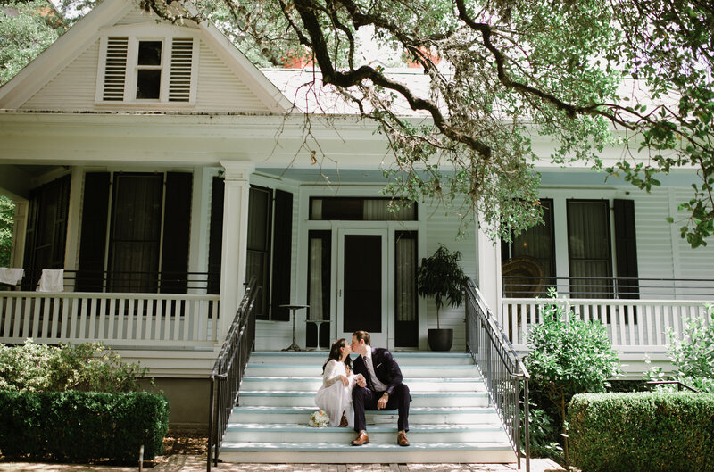 Couple sitting on front steps of a house kissing, Austin elopement wedding