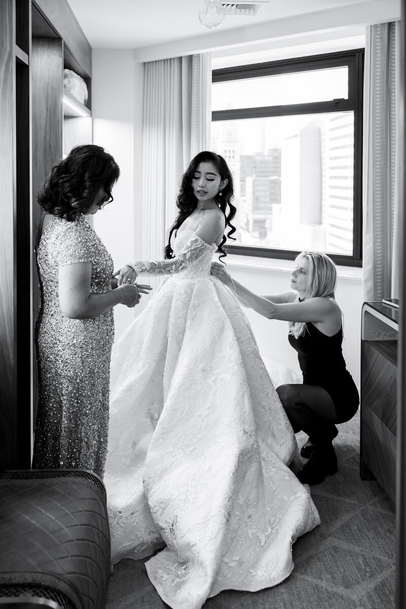 Groom looks at bride's dress in awe while she laughs during their first look