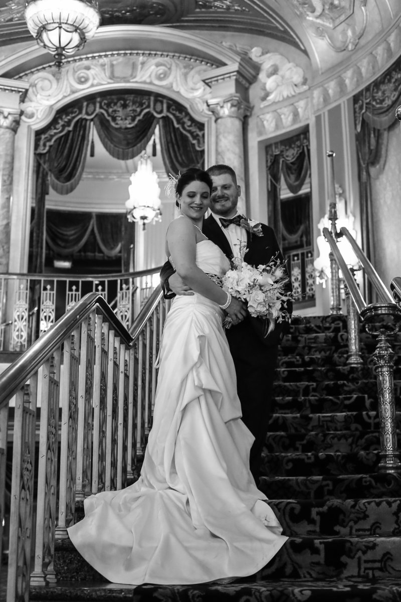 Bride and groom stand on grand staircase at their Warner Theater wedding in Erie, PA