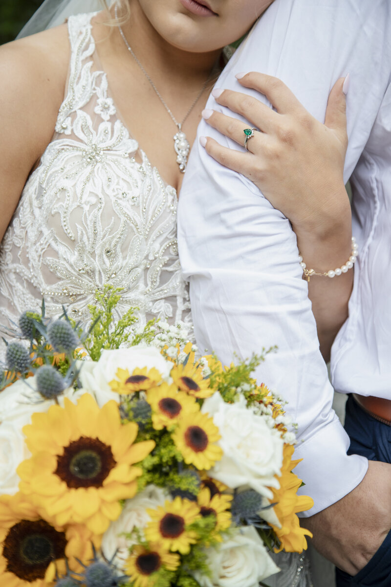 bride and groom with arms linked while bride holds a bouquet of sunflowers