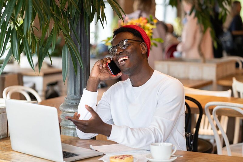 Millenial talking on phone in front of computer to illustrate how to get high-paying clients on Upwork