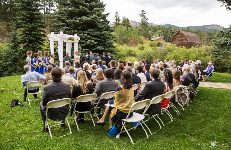 Wedding ceremony in Colorado Mountain Meadow with Barn in Distance