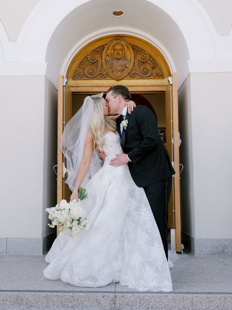 Wedding reception tables set up in an outdoor arched corridor overgrown with ivy