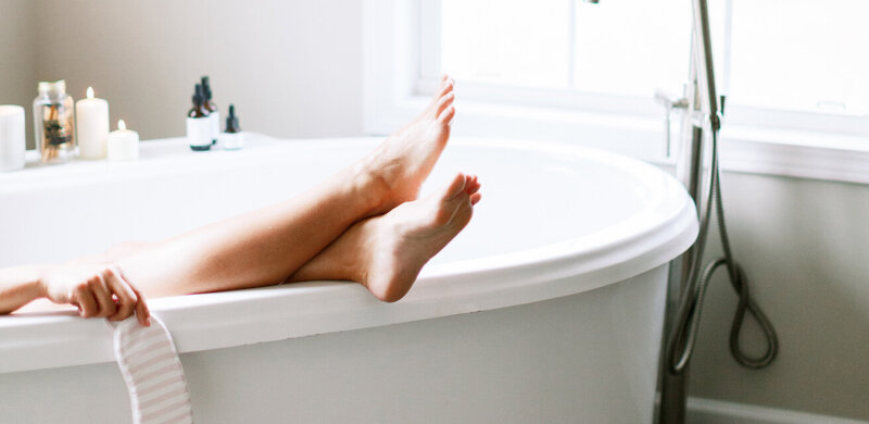 A lady in a claw bathtub with her feet on the rim relaxing