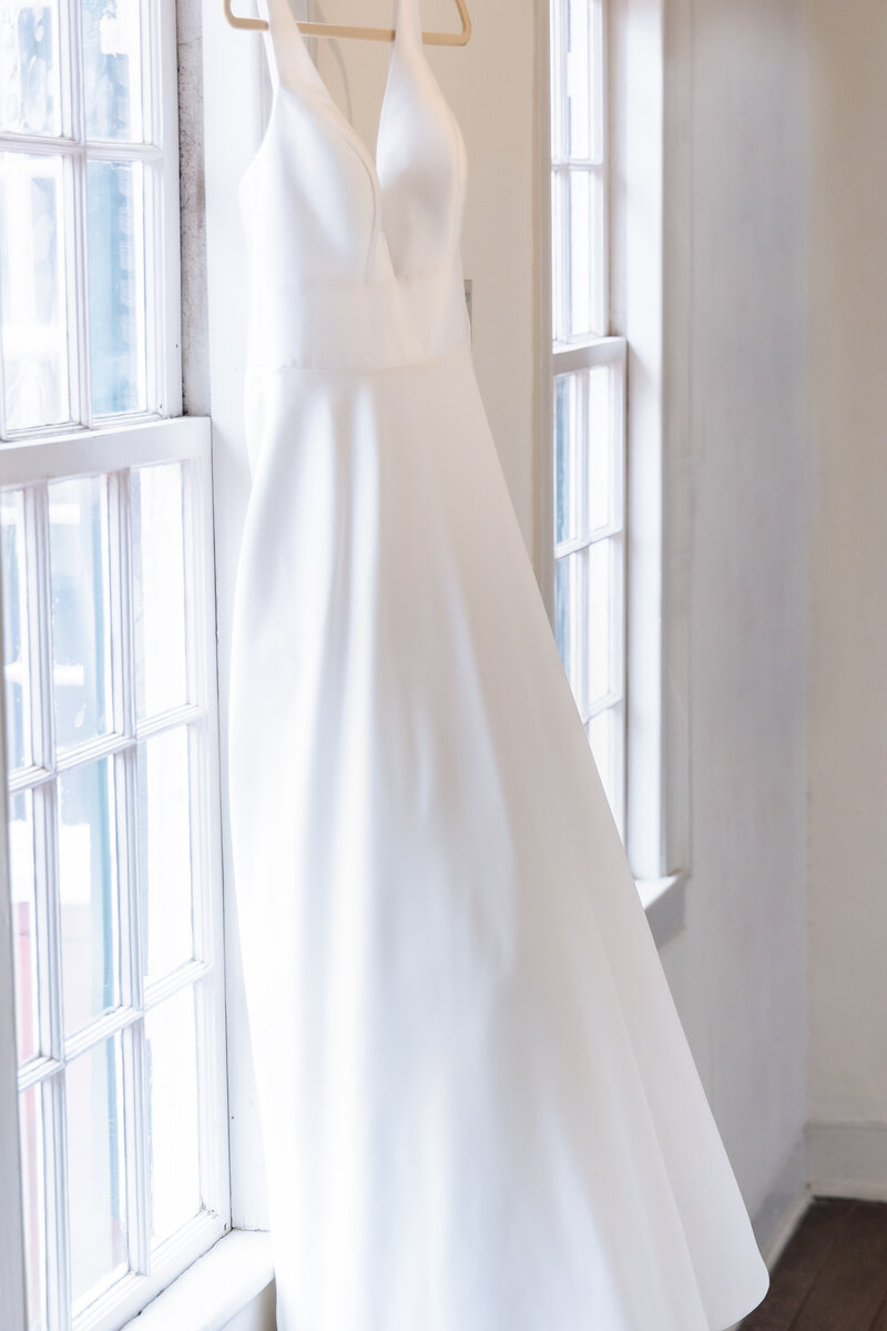 wedding dress hanging by window