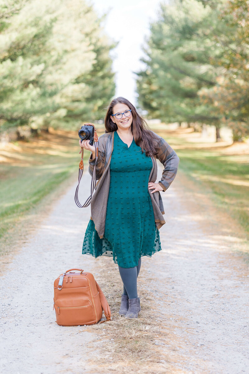 Kate Legters standing at White Oak Farm holding her camera and camera bag.