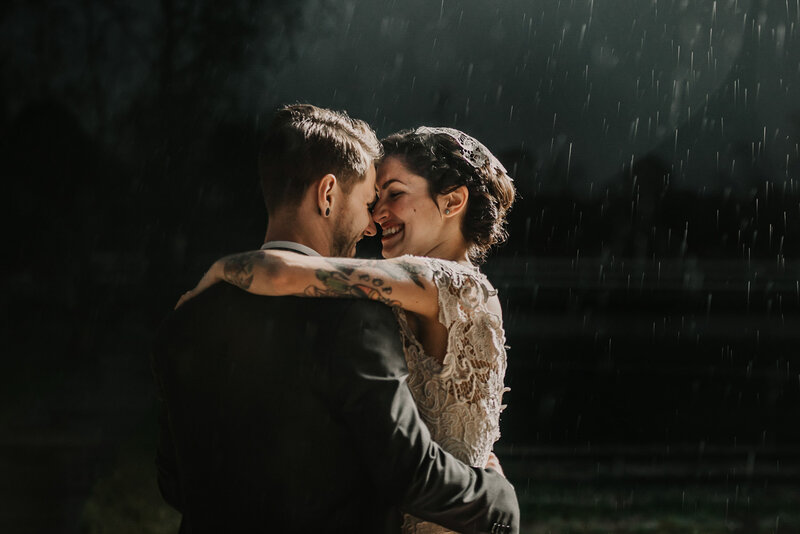 A photograph of a bride and groom having their first dance in the rain.