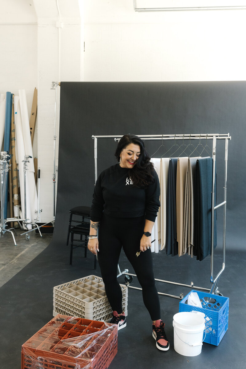 Woman dressed in all black and wearing air jordans standing in a photography studio in front of event rentals and linens
