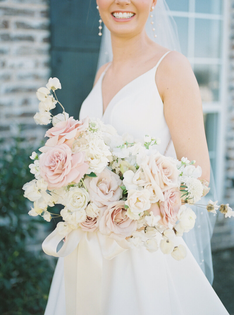 A Dallas bride holding a bouquet of white and bush roses