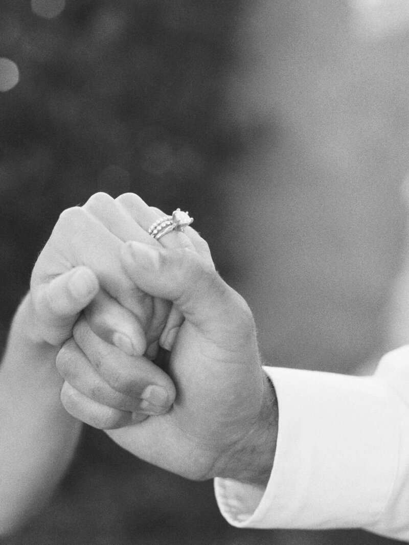 black and white image of groom holding bride's hand
