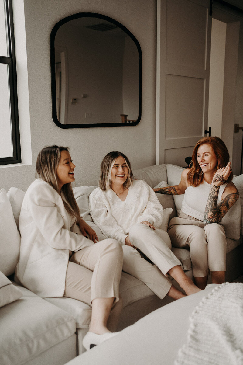 Three girls sitting on a couch as they chat and laugh